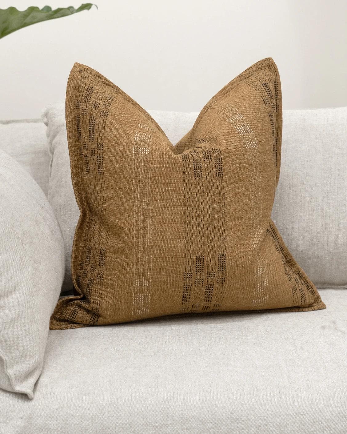 Yon Ochre cushion in ochre brown, shown in a lifestyle front view as image 2